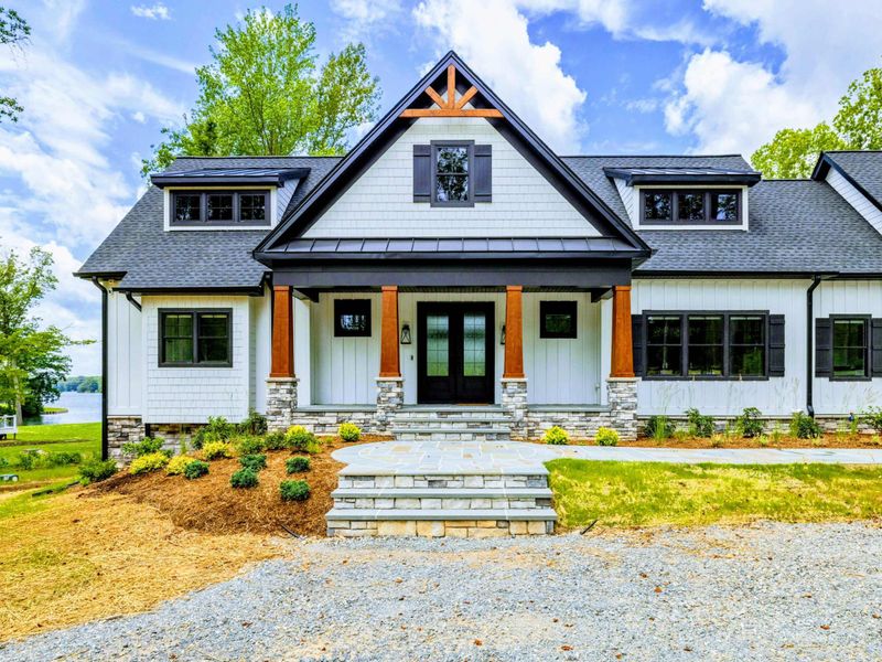 Front Exterior - The custom modern farmhouse features cedar timber accents, stone steps, and a welcoming covered front porch.