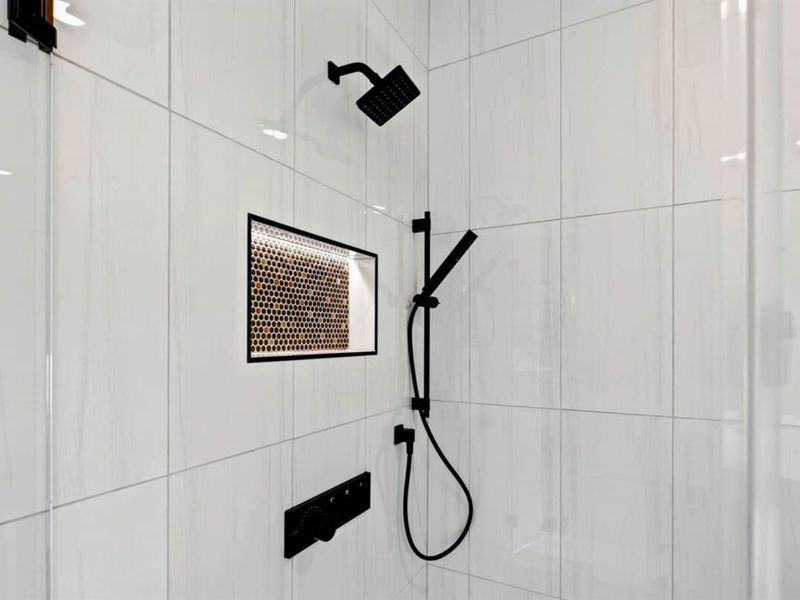 Primary Bathroom - Matte black fixtures, a rain showerhead, and a penny-tile niche bring modern elegance to the walk-in shower.