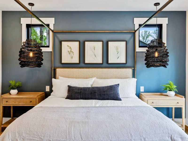 Primary Suite - Botanical art, woven pendant lights, and a blue accent wall frame the canopy bed for a restful retreat.