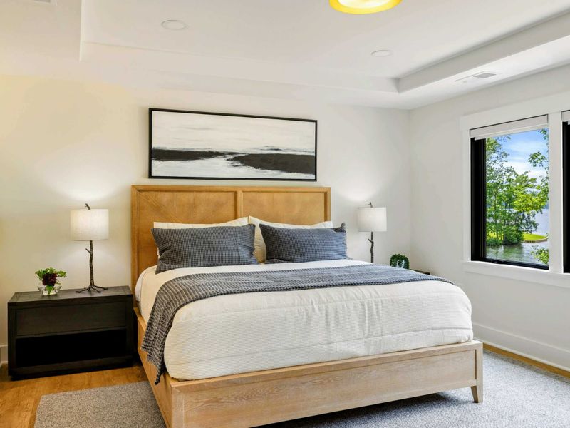 Bedroom 4 - Blue and gray bedding, a reading chair, and lake views create a serene main-level retreat.