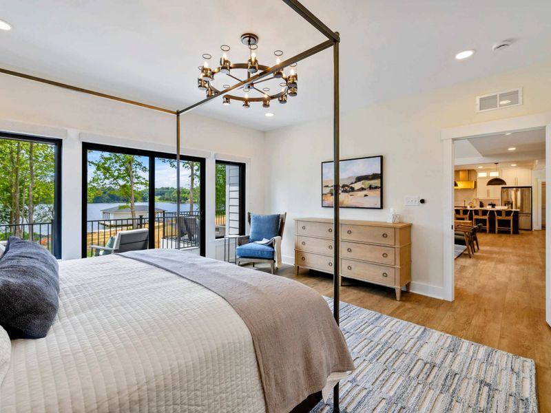 Primary Suite - The king bed faces sliding glass doors to a private balcony overlooking the lake and the open living area beyond.