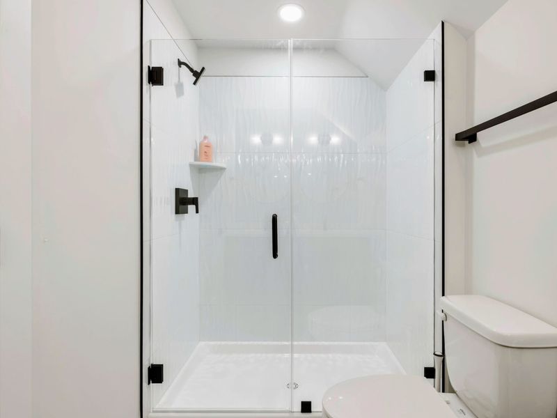 Bathroom 5 - A glass-enclosed walk-in shower with clean white tile and matte black hardware completes this en-suite.