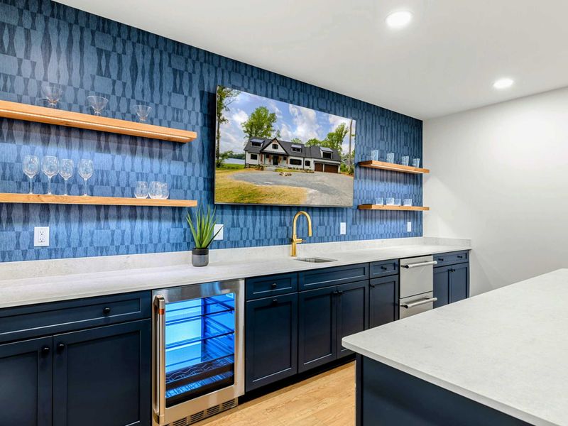 Wet Bar - A beverage refrigerator, gold fixtures, and elegant blue tile backsplash keep drinks and snacks within easy reach.