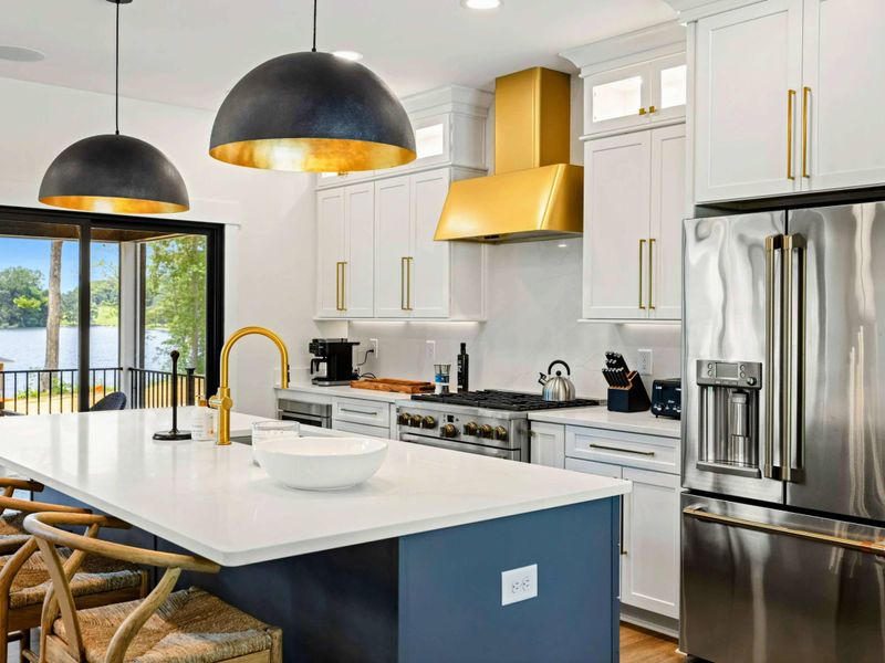 Kitchen - Woven counter stools, a navy island, and a brass hood create a warm, inviting space to gather while meals come together.