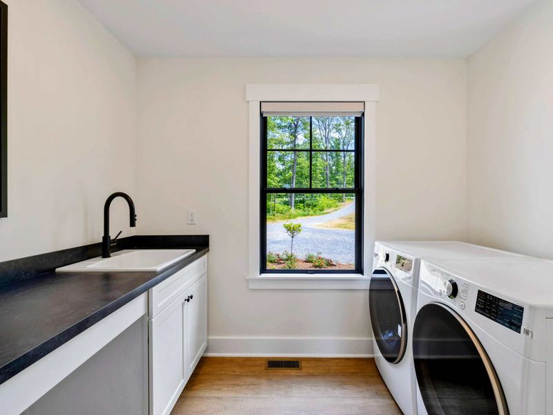 Laundry Room - A utility sink with black countertop and ample cabinet storage complete this well-equipped laundry space.