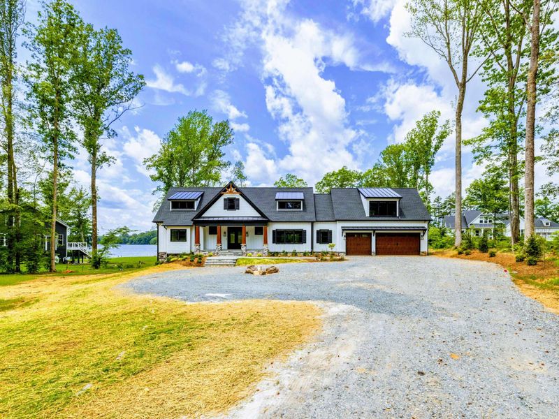 Front Exterior - The full facade with attached two-car garage, gravel circular drive, and mature tree canopy.