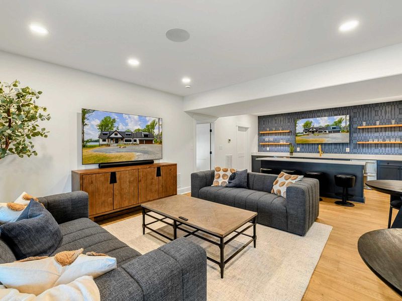 Game Room Lounge - Two plush sofas face a large screen TV with a soundbar, creating a cozy movie night setup on the lake level.