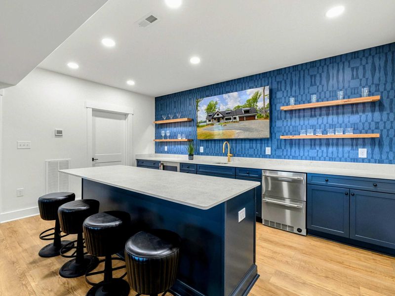 Wet Bar - Navy blue cabinets, blue geometric tile, floating wood shelves, and four leather bar stools create a stylish entertaining hub.