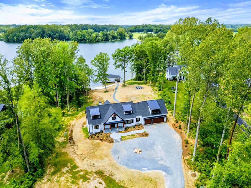 Aerial View - A bird's-eye view reveals the home, circular driveway, boathouse, and 200 feet of private shoreline.