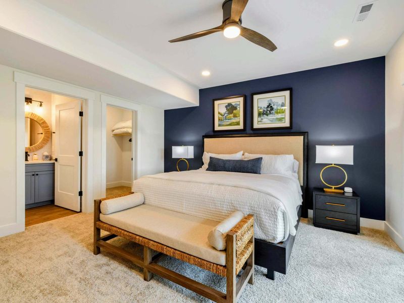 Bedroom 2 - A navy accent wall, woven bench, and ceiling fan create a comfortable private retreat with en-suite access.