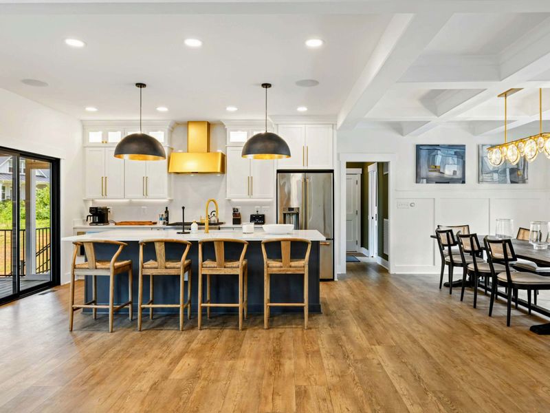 Kitchen - A navy blue island with woven counter stools seats four beneath oversized black and gold pendant lights.