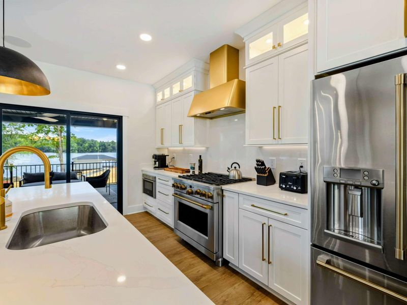 Kitchen - Professional-grade appliances, gold fixtures, and lake views through the sliding doors make this a cook's retreat.