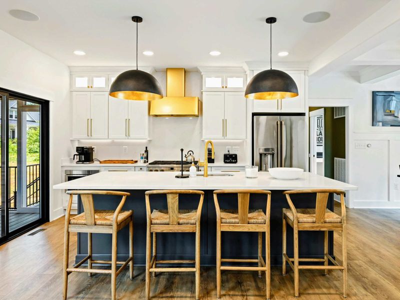 Kitchen - The chef's kitchen features a brass range hood, professional gas range, and quartz countertops throughout.
