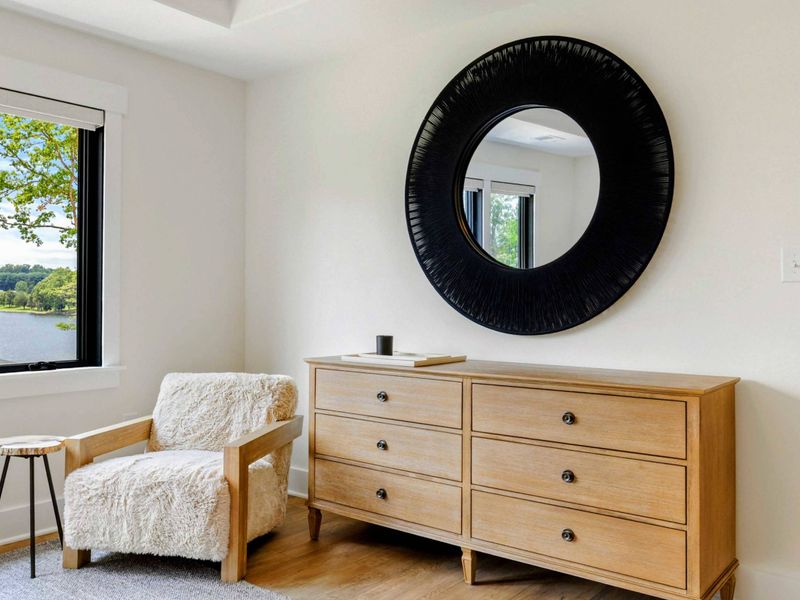 Bedroom 4 - A cozy sherpa chair and round mirror sit beside the window, offering a quiet reading nook with lake views.