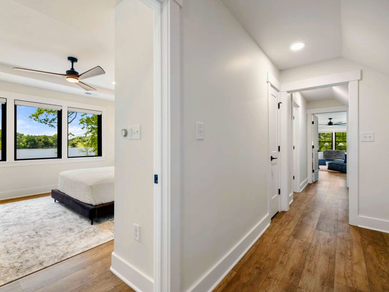 Hallway - Hardwood floors connect the upper-level bedrooms with glimpses of lake views through each doorway.