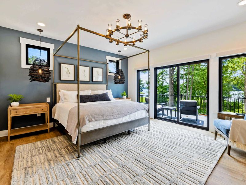 Primary Suite - A gold canopy bed, rattan pendant lights, and a deep blue accent wall set a luxurious tone with private balcony access.