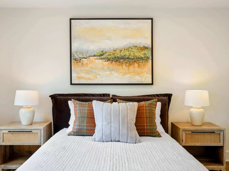 Bedroom 6 - Plaid accent pillows, ceramic lamps, and a landscape painting give this upper-level suite a refined lakehouse feel.