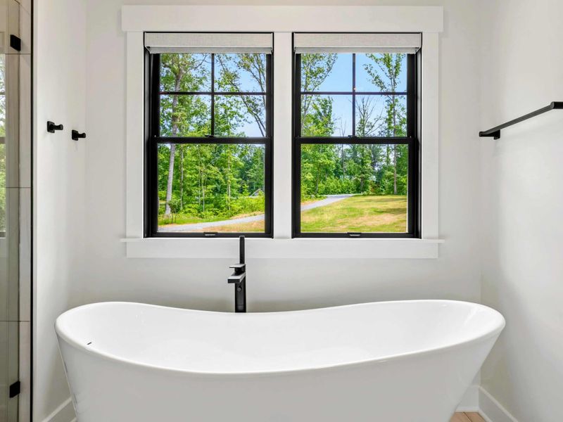 Primary Bathroom - Soak in the freestanding tub while taking in views of the surrounding trees and natural light.