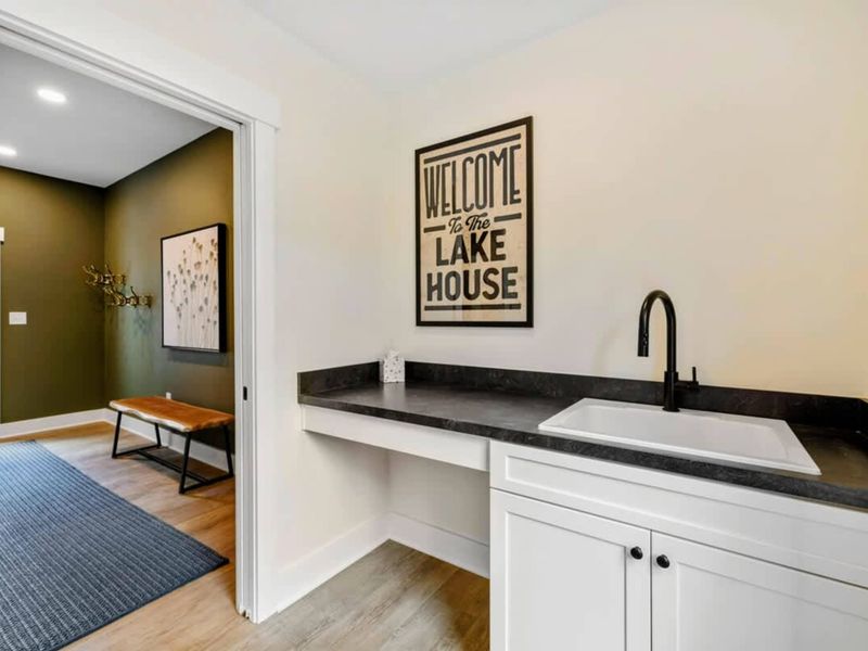 Mudroom - A "Welcome to the Lake House" sign greets guests near the utility sink and bench, connecting to the main entry.