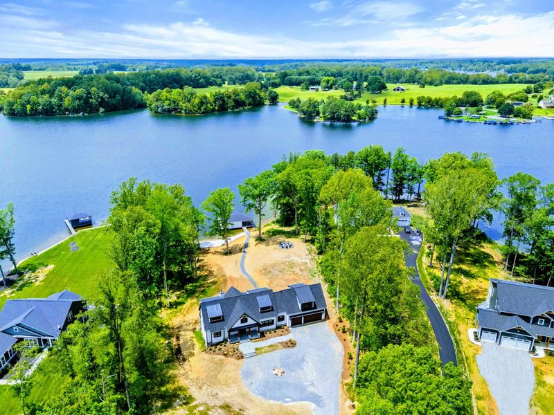 Aerial View - The property sits on a generous lakefront lot with the cove, boathouse, and neighboring homes visible.