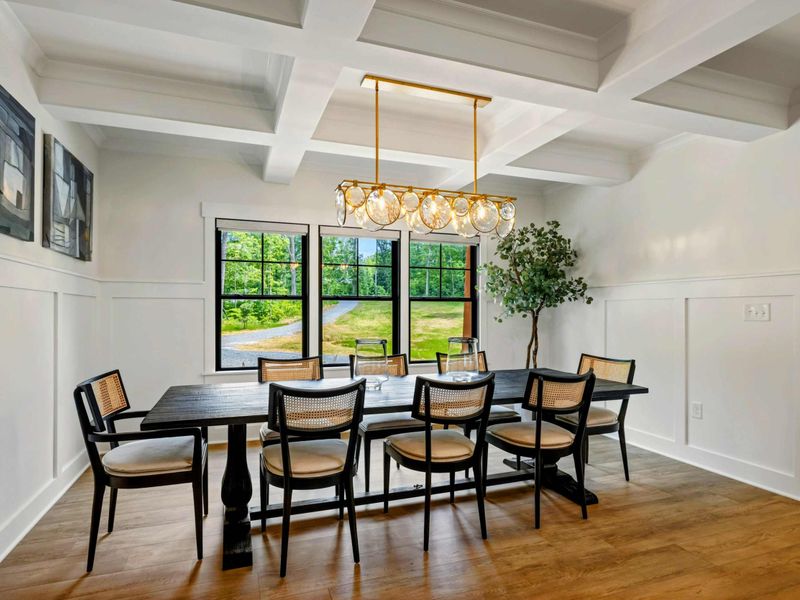Dining Room - Three large windows bring in natural light while wainscoting and a statement chandelier set a refined tone.