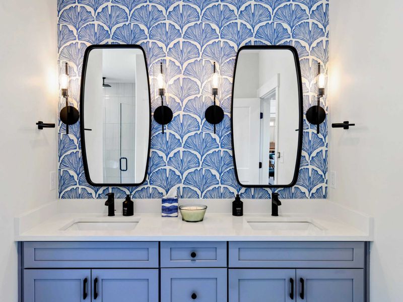 Primary Bathroom - Dual sinks, black-framed mirrors, and a striking blue and white wallpaper accent create a spa-like feel.