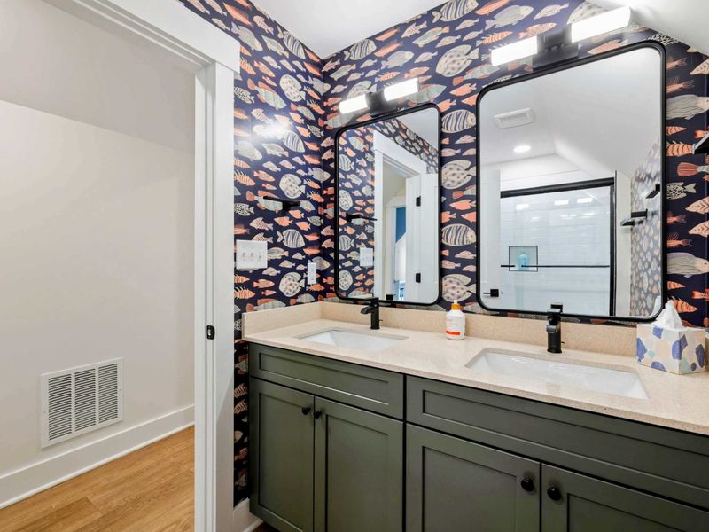 Jack-and-Jill Bathroom - Playful fish wallpaper, a green double vanity, and dual mirrors bring coastal charm to this shared bath.