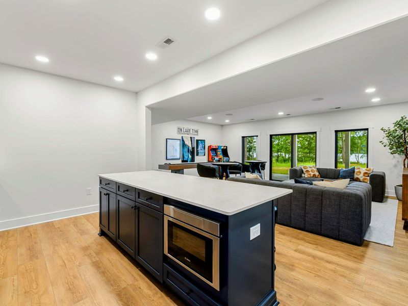 Wet Bar - The island includes a built-in microwave and opens to the shuffleboard and lounge area beyond.