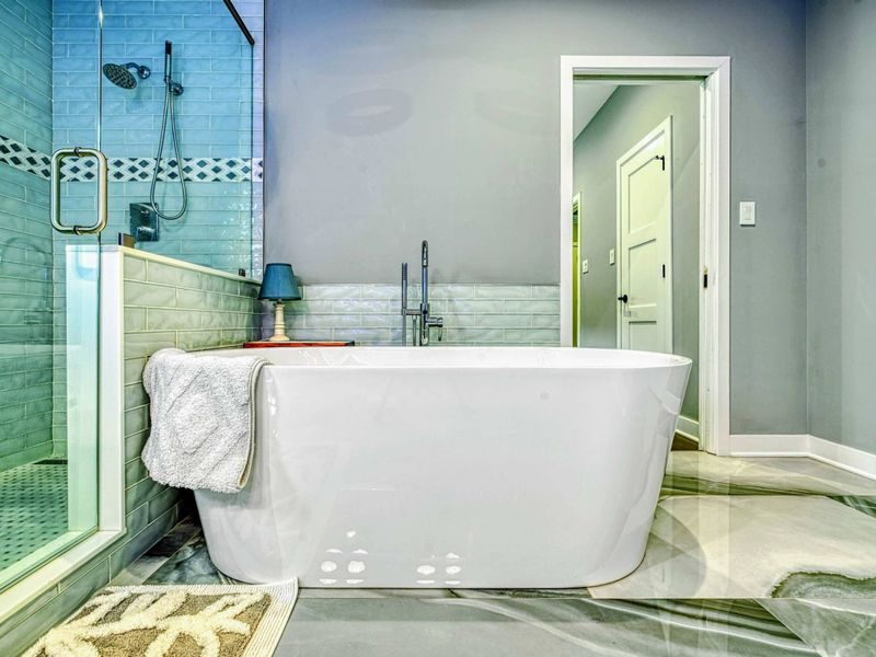 Guest Bathroom - A freestanding soaking tub beside a glass-enclosed shower with subway tile and diamond accent band, marble floors, and soft blue-purple ambient light.