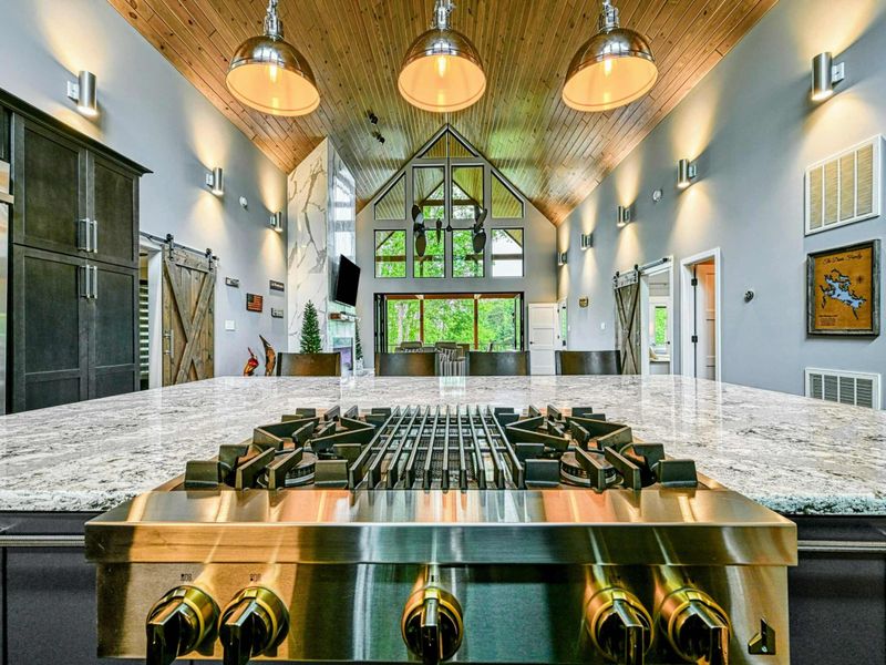 Kitchen Range - From behind the six-burner gas range, the view stretches across the island through the great room to the screened porch and lake beyond.