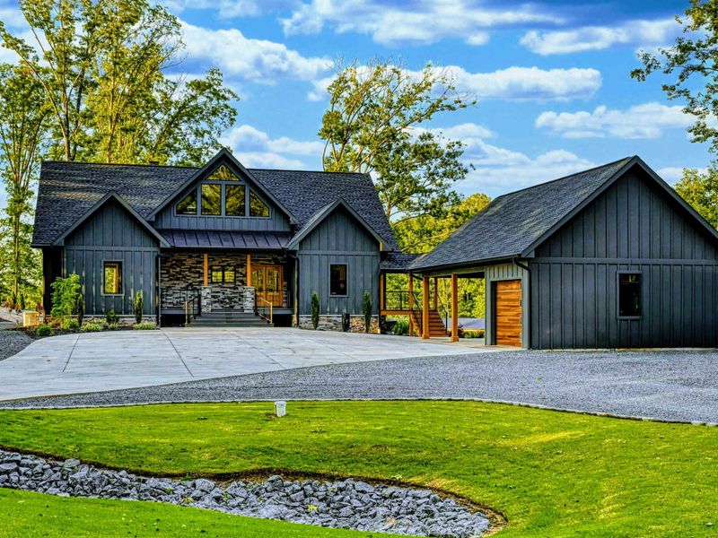 Front Aerial - An aerial view shows the full property layout with the main home, detached garage, circular driveway, and manicured green lawn.