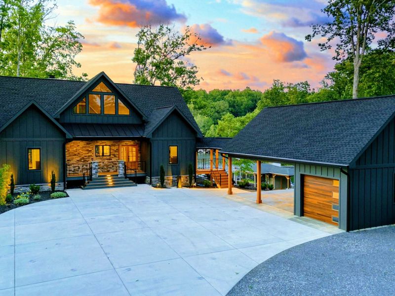 Twilight Driveway - The full property at dusk with the main home, detached garage, circular driveway, and warm exterior lighting against a cotton candy sky.