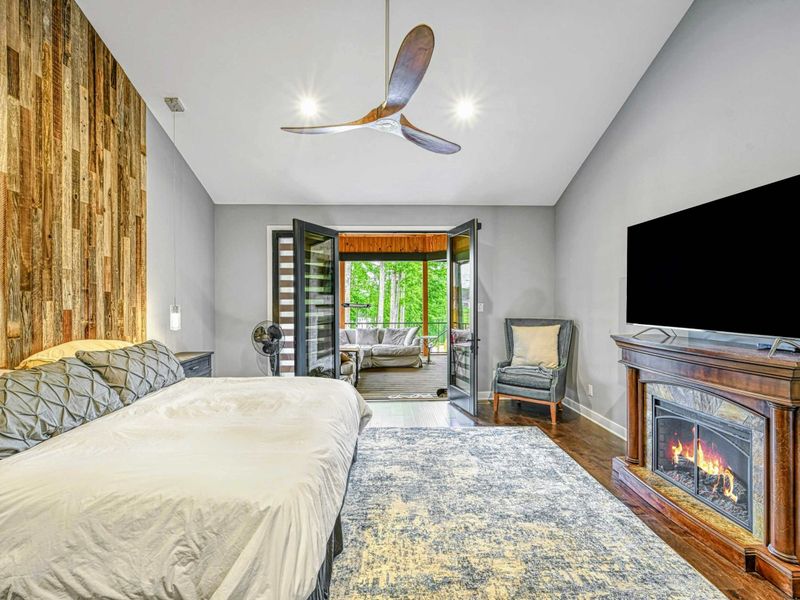 Primary Suite - A king bed with a reclaimed wood accent wall, electric fireplace, Smart TV, and French doors opening to the screened porch.