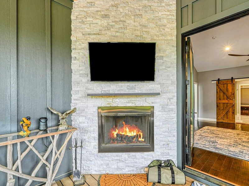 Outdoor Fireplace - A stacked stone fireplace with a Smart TV, flanked by driftwood accent tables, anchors the turret lounge with a roaring fire.