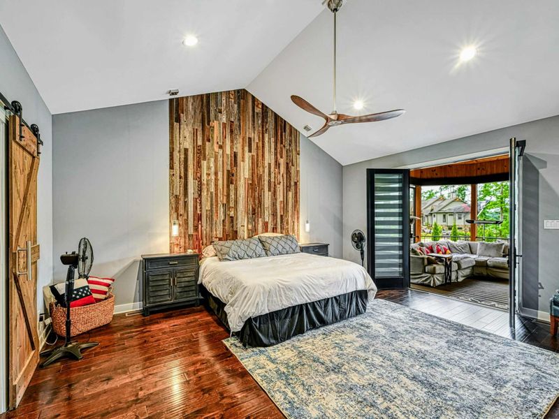 Primary Suite - The spacious king bedroom features a barn door entry, modern ceiling fan, reclaimed wood wall, and porch access.