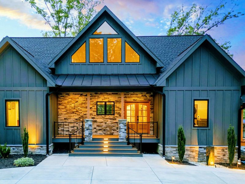 Front Entry at Dusk - Warm light pours through the stone-framed entry and A-frame peak as the home glows against the twilight sky.