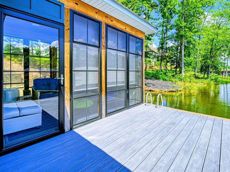 Dock Lounge Entry - Sliding glass doors open from the dock platform into the screened lounge, with blue cushioned seating visible inside.