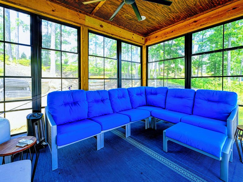 Screened Dock Lounge - A blue sectional sofa fills the screened-in dock room, creating a bug-free lakeside lounge with ceiling fan.