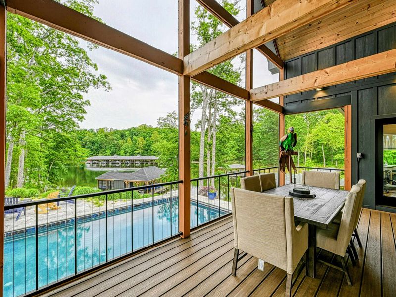 Screened Porch Dining - A farmhouse dining table for eight sits on the screened porch beneath the timber A-frame, with pool and lake views.