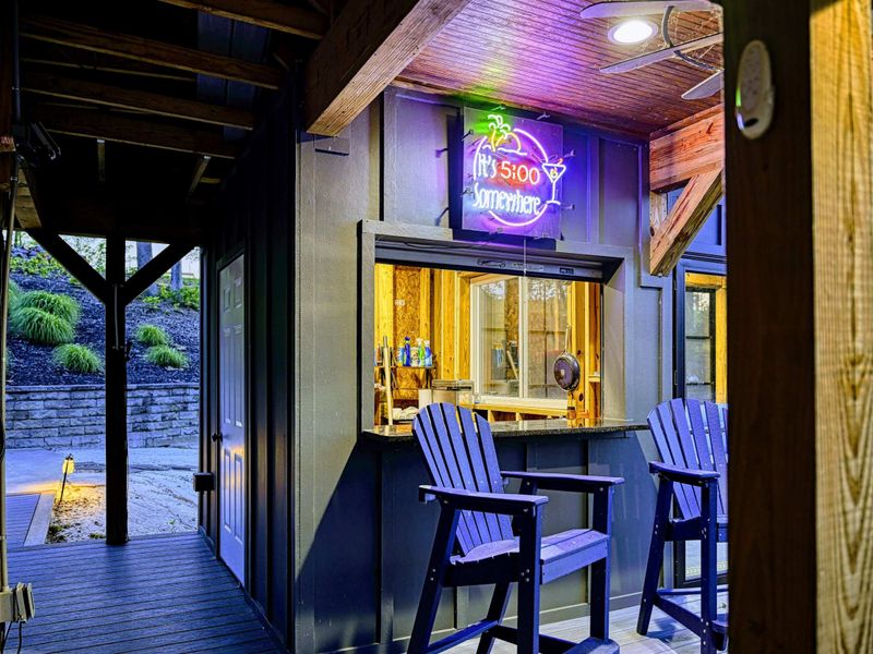 Dock Bar at Night - The cocktails bar neon sign casts a purple glow at twilight, with Adirondack chairs and the boat slip framed by timber posts.