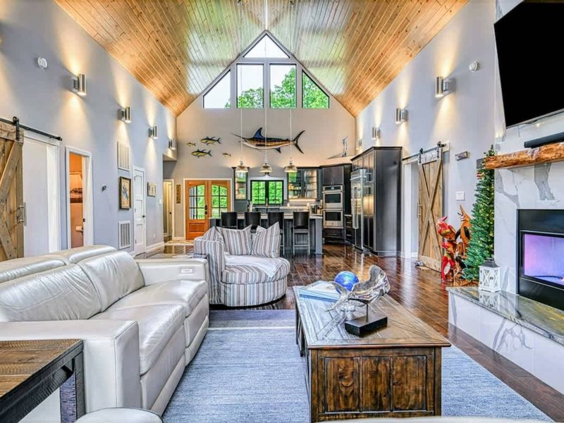 Great Room Panorama - The entire open-concept main floor, from the marble fireplace to the kitchen island, soaring pine ceilings, and mounted marlin decor.