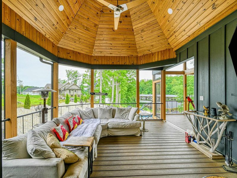 Turret Lounge - A cozy sectional sofa, Smart TV, and stone fireplace fill the screened turret room, topped by a stunning wood-paneled conical ceiling.