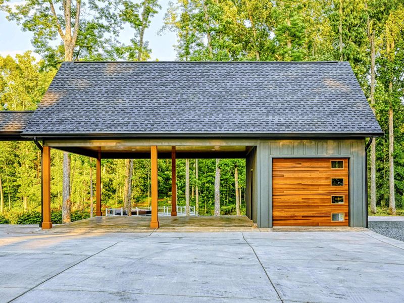 Garage - A detached garage with a cedar wood door, covered carport, and matching dark siding complements the main home's modern craftsman style.