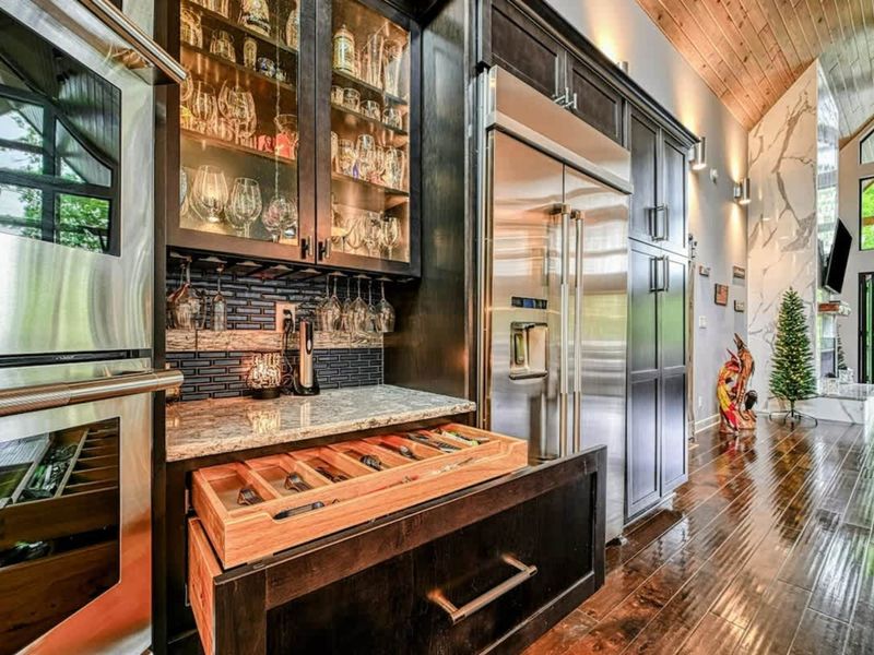 Kitchen Bar - The glass-front bar cabinet and custom cedar-lined drawer with a full collection of spirits and cocktail supplies sit beside the refrigerator.