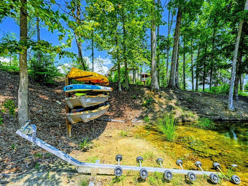 Kayak Storage - Colorful kayaks stacked on a rack beside the stone path, ready to launch from the shoreline.