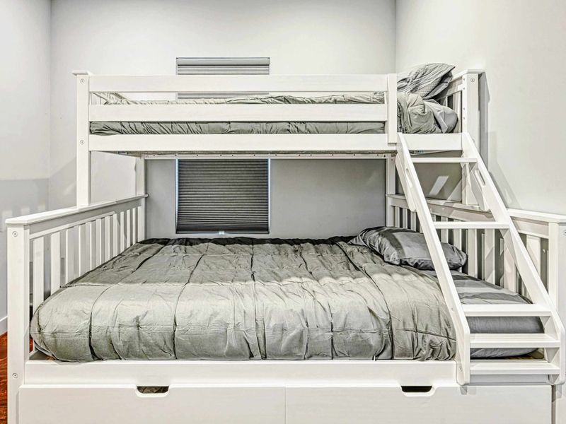 Bunk Room - A white twin-over-full bunk bed with gray bedding and built-in storage drawers in a clean, comfortable room.