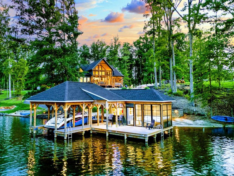 Waterfront at Twilight - Ober The Lake glows warmly from the hillside, with the covered dock and boathouse lit up on the water at sunset.
