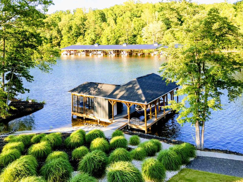 Lakefront Overlook - From the upper grounds, ornamental grasses frame the view down to the boathouse, dock, and calm lake waters.