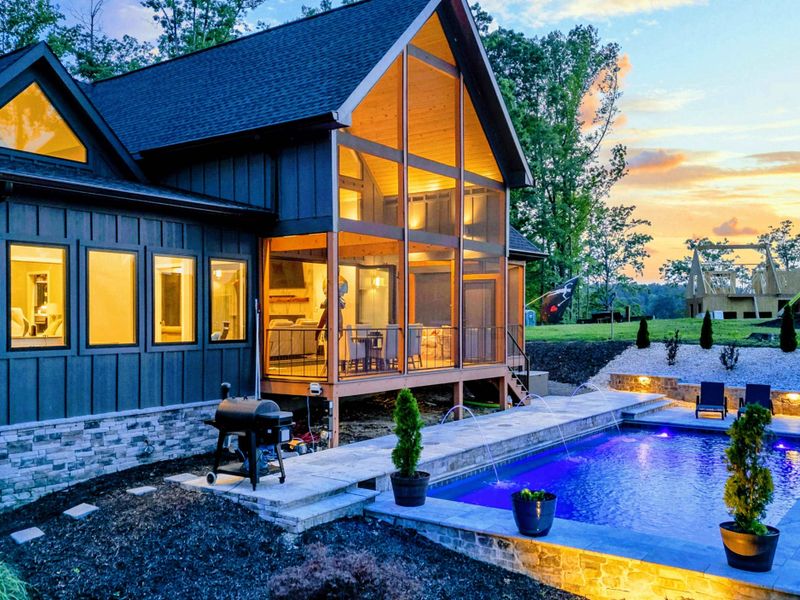 Twilight Exterior - At dusk, warm light pours through the A-frame glass wall as the pool glows beside the home, with pathway lighting throughout.