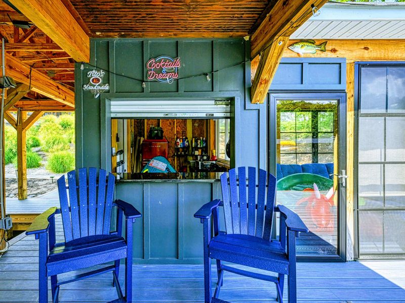 Dock Bar - Blue Adirondack chairs belly up to the cocktails bar with a neon sign, right on the covered dock with lake views.